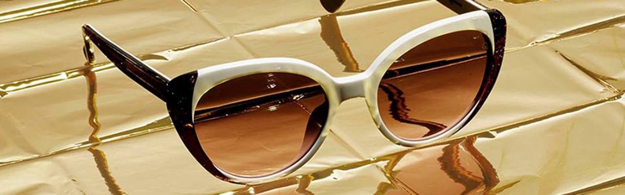 a pair of dark sunglasses on a gold-foil background